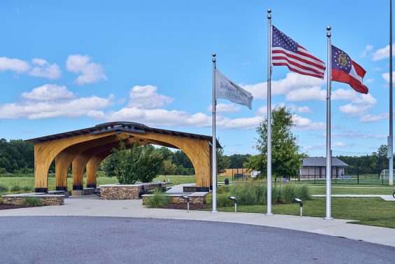 A Georgia state and Johns Creek fly on flagposts outside the entrance of a Johns Creek park.