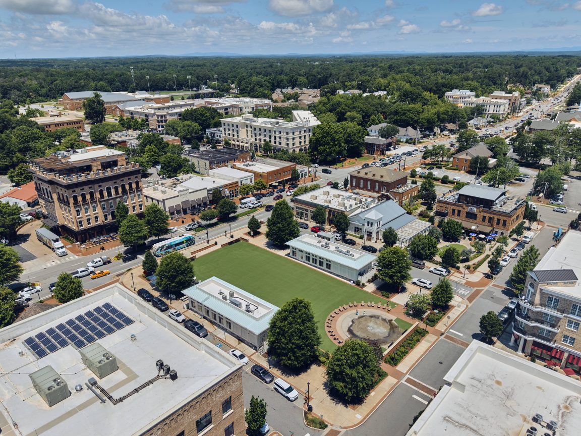 Arial view of downtown Alpharetta, many buildings surrounding a green lawn.